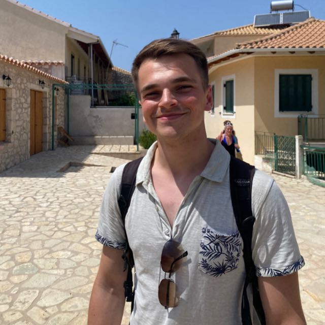 Image of Shawn, smiling on a sunny day in Greece.